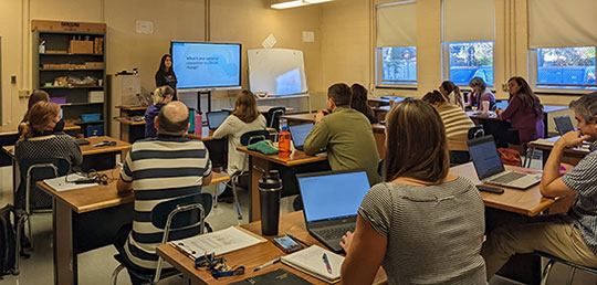teachers watching presentation in classroom