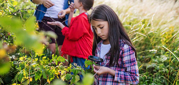 student looking through magnifying glass